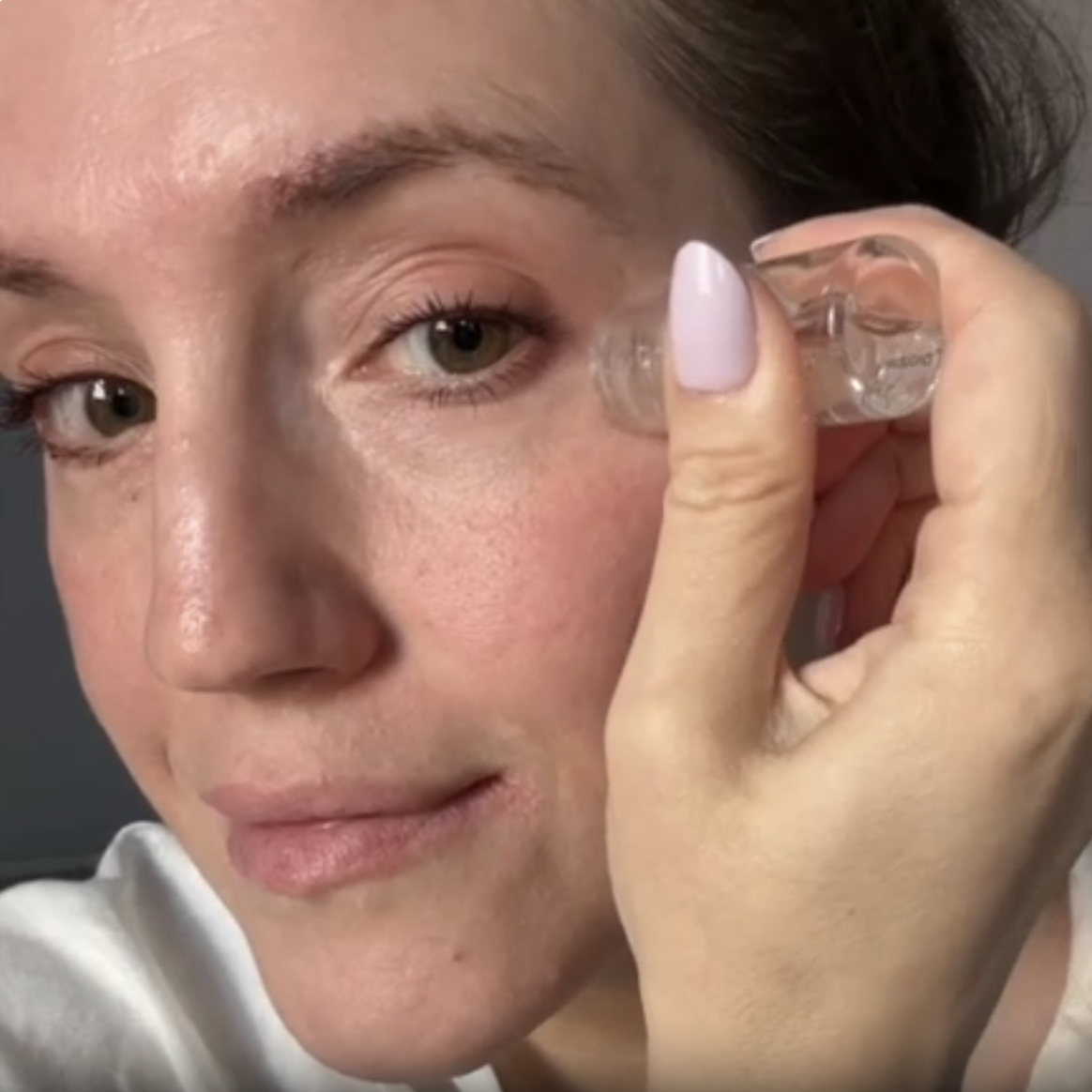 Woman using a needle-free infusion device on her cheek to deliver skincare actives deep into the skin