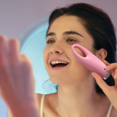 Woman gently applying a sonic eye massager to the under-eye area to reduce puffiness and improve absorption