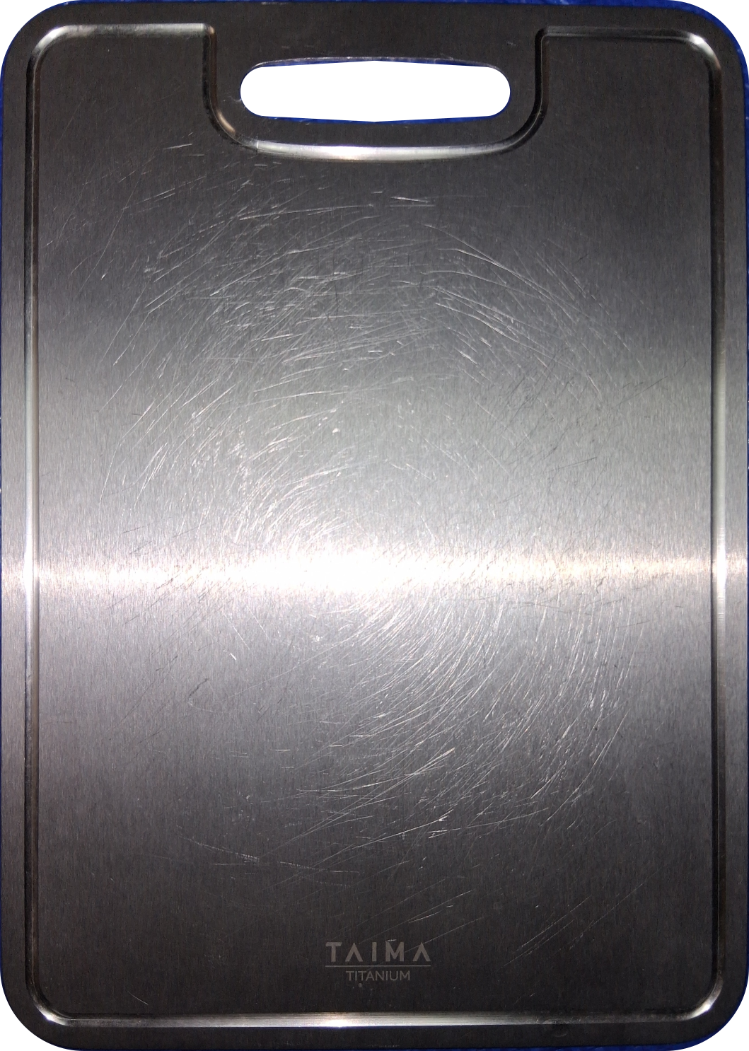 Taima Titanium Cutting Board V2 after more than one year of regular use showing fine cosmetic knife marks with no deep grooves, staining, or warping