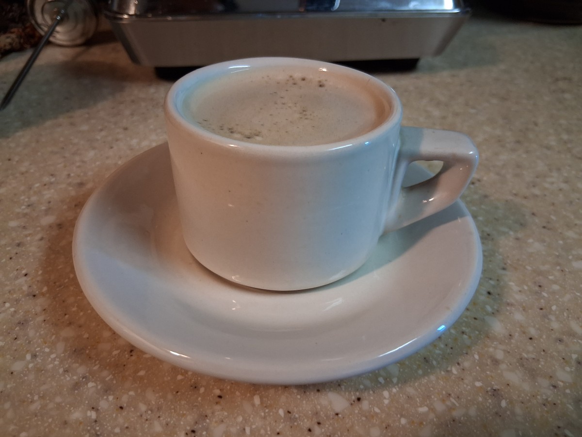 Freshly brewed espresso with a light layer of crema in a white ceramic cup and saucer, prepared using the AMZCHEF CM1626