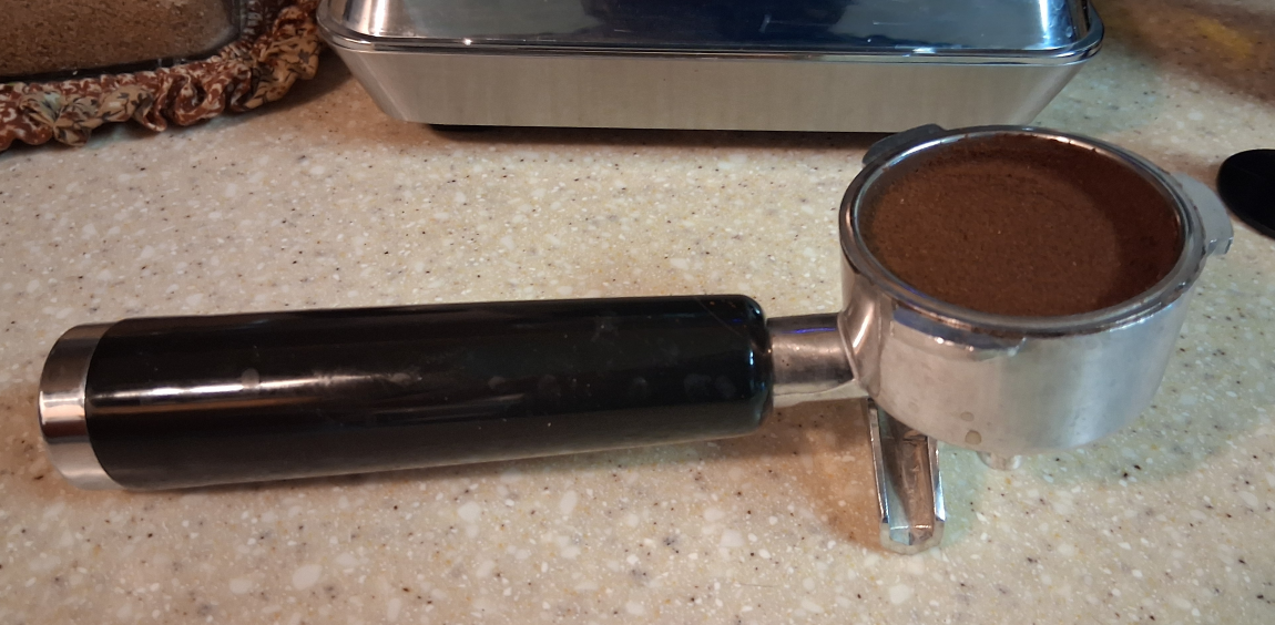 AMZCHEF CM1626 portafilter filled with ground coffee, shown on a countertop before brewing