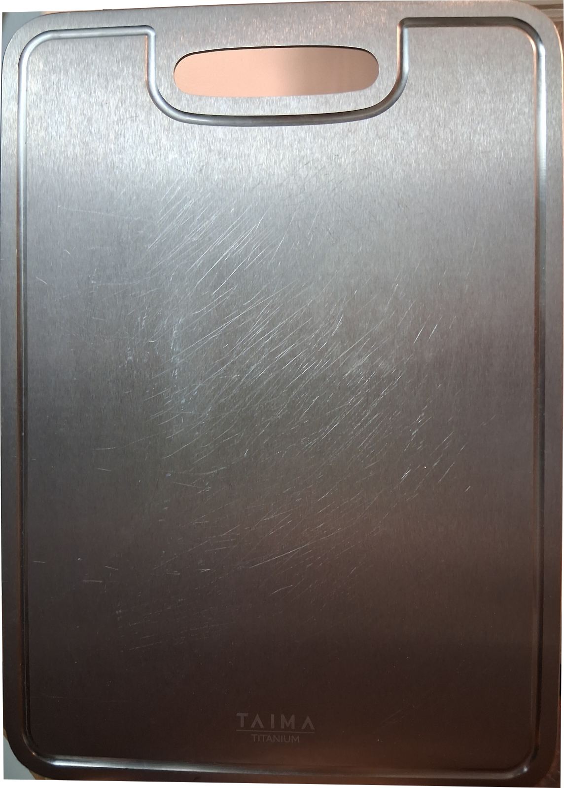 Taima Titanium Cutting Board V2 after 9 months of near-daily use showing typical cosmetic surface scratches with no staining or warping